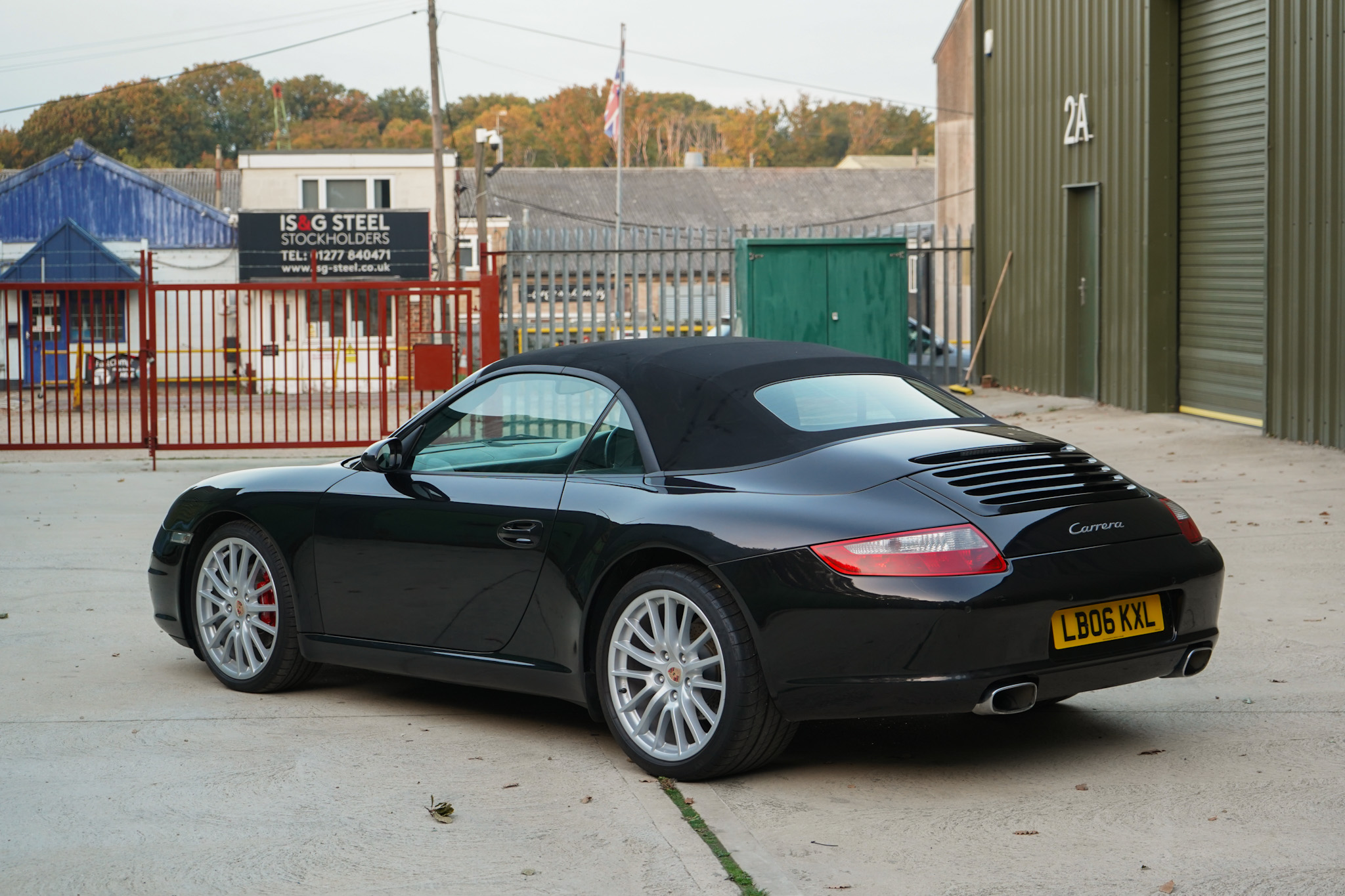 Black 2006 Porsche 911 (997) Carrera Cabriolet in a wide rear three-quarter view.