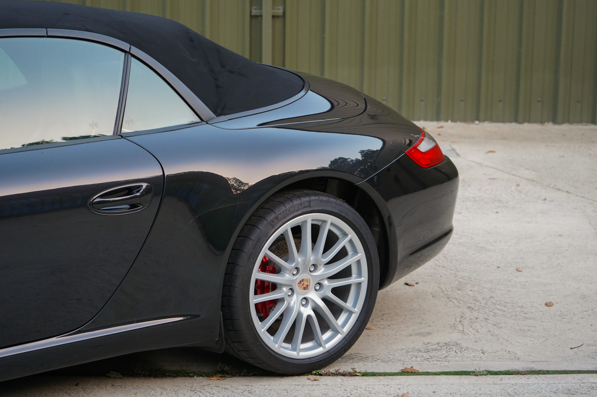 Black 2006 Porsche 911 (997) Carrera Cabriolet showing the rear wheel and quarter close-up.
