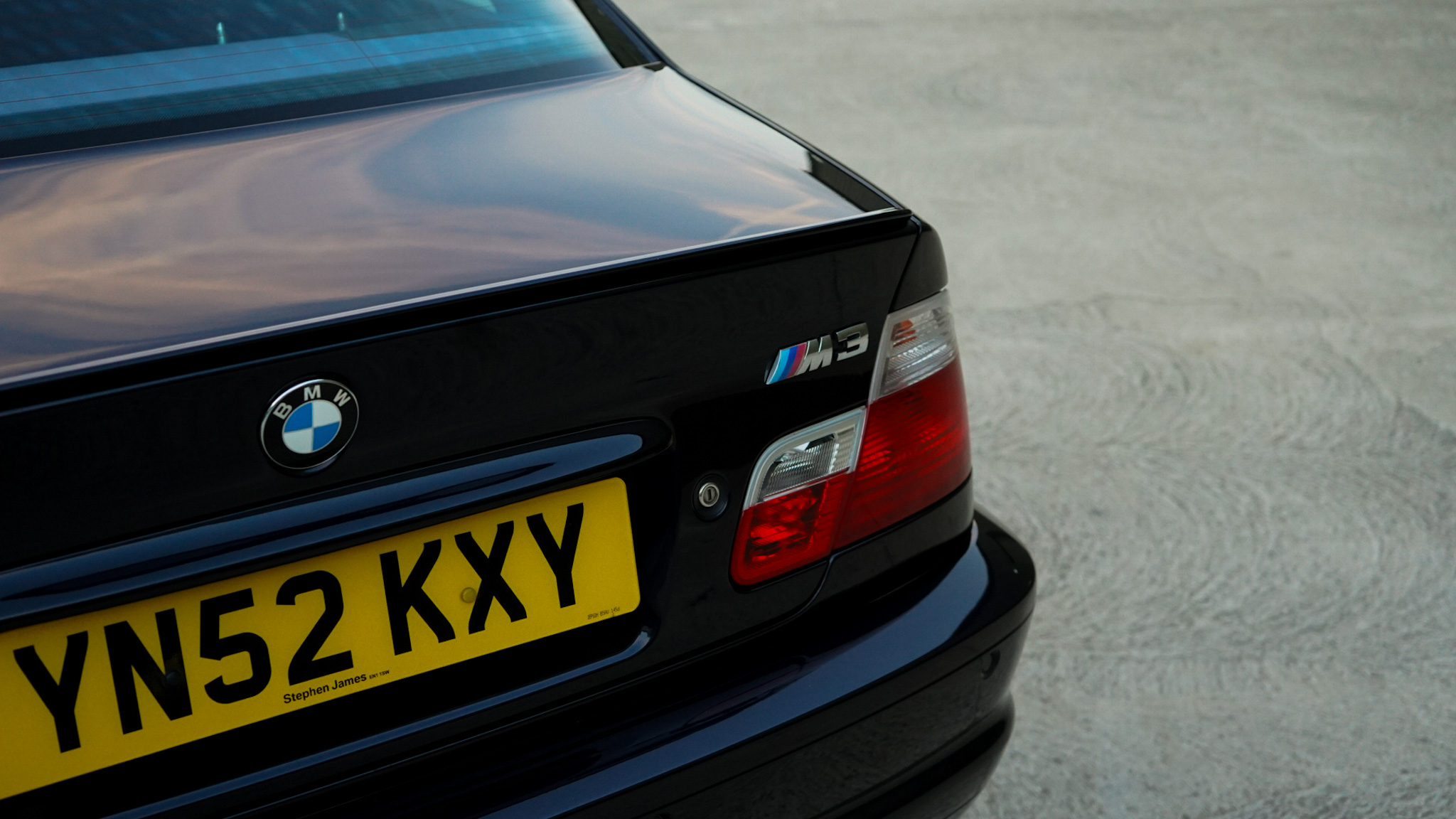 Black 2002 BMW M3 (E46) Manual showing the rear badge and taillight close-up.