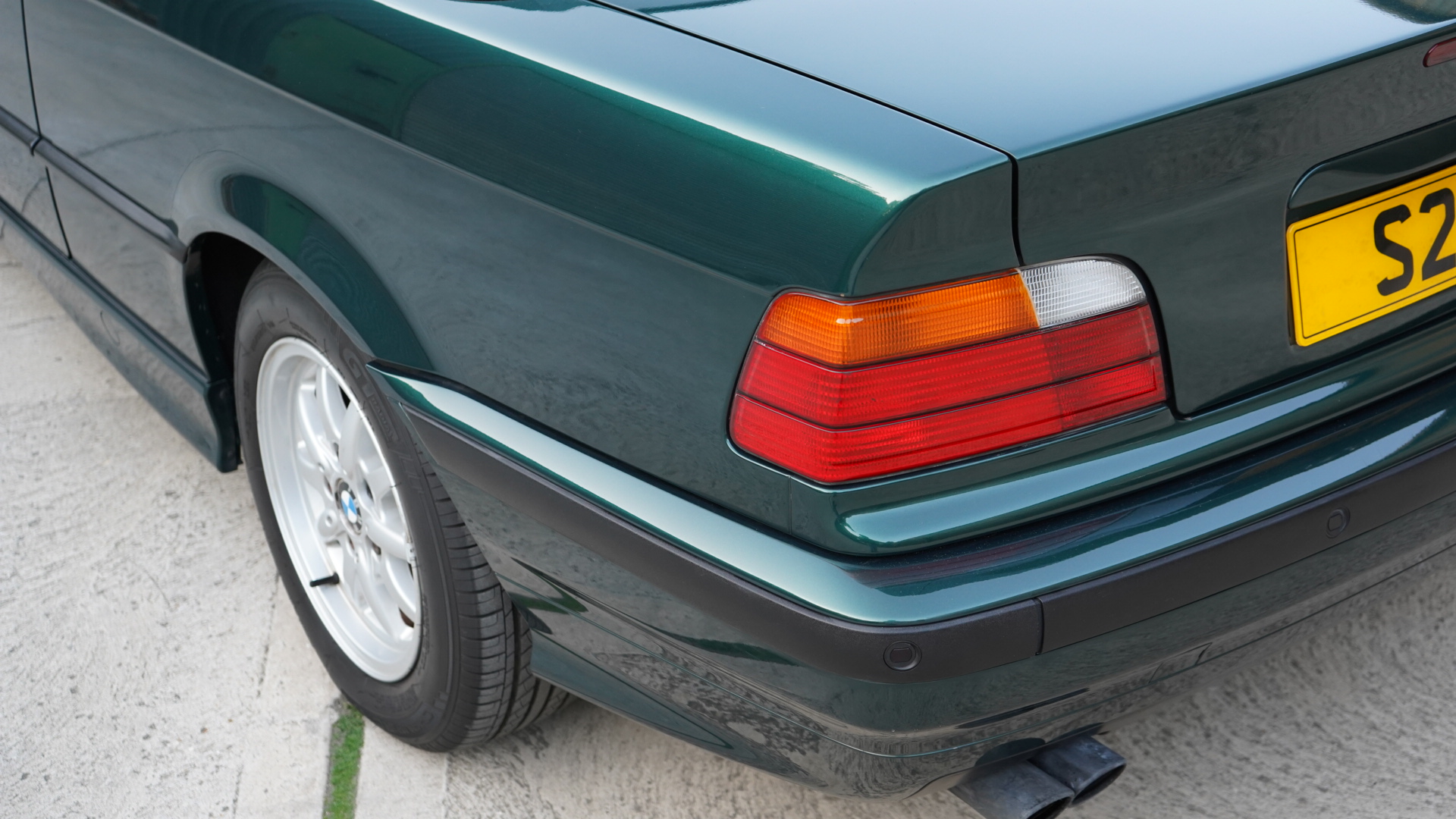 Dark green BMW 328i (E36) Manual Convertible showing the rear quarter and taillight from a high angle.