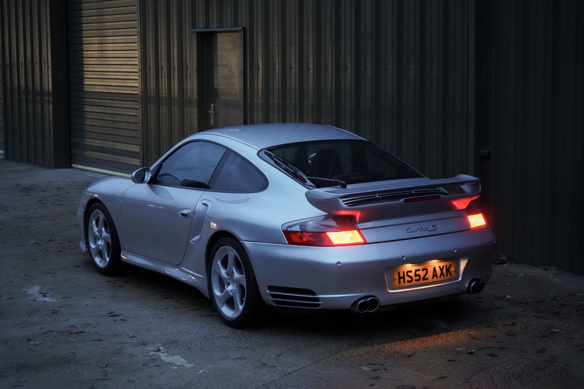Silver Porsche 911 (996) Turbo X50 Pack in a alternate rear three-quarter view with the taillights illuminated.