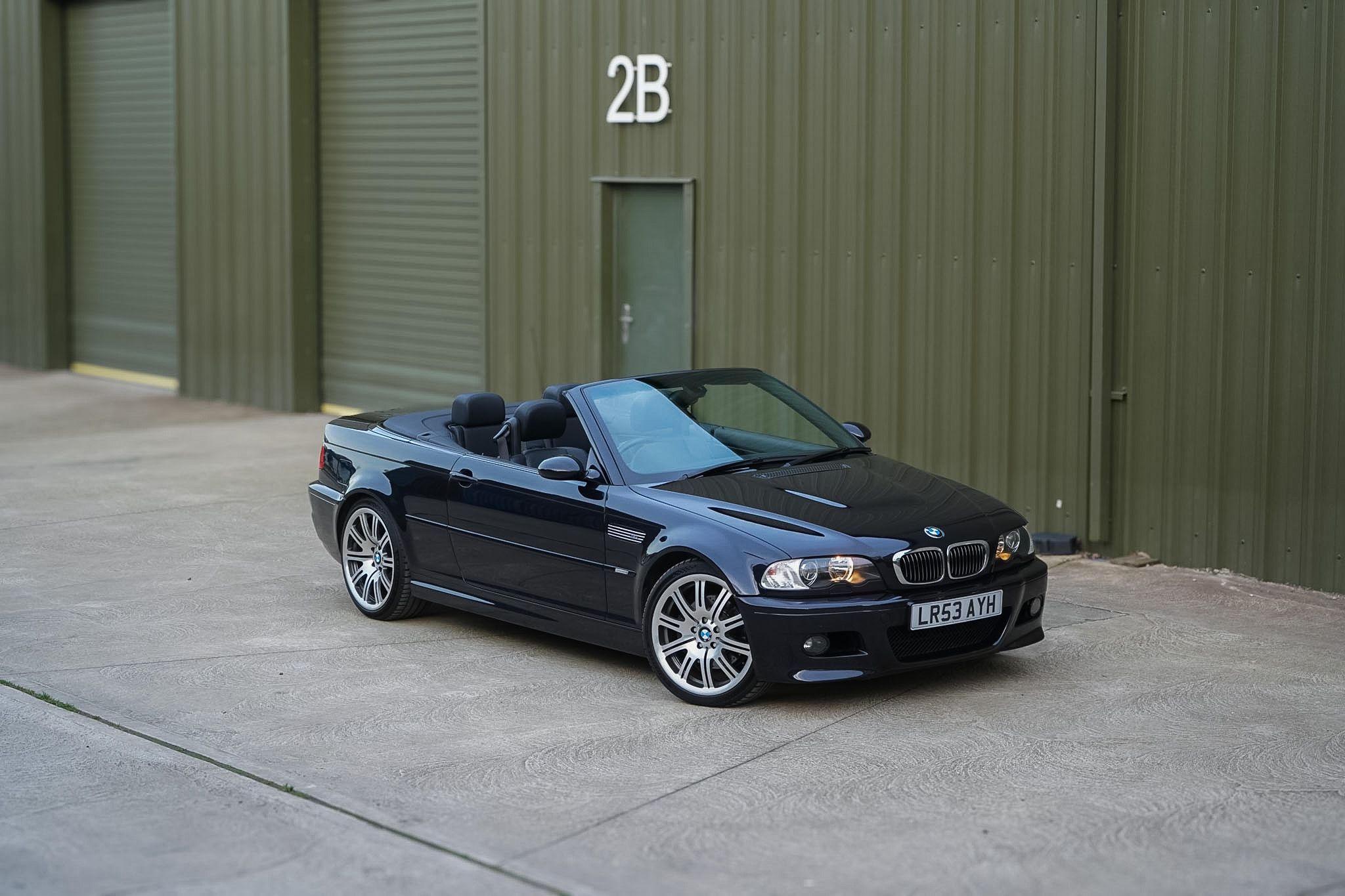 Carbon Black 2003 BMW M3 (E46) Convertible in a front three-quarter view with the roof lowered.