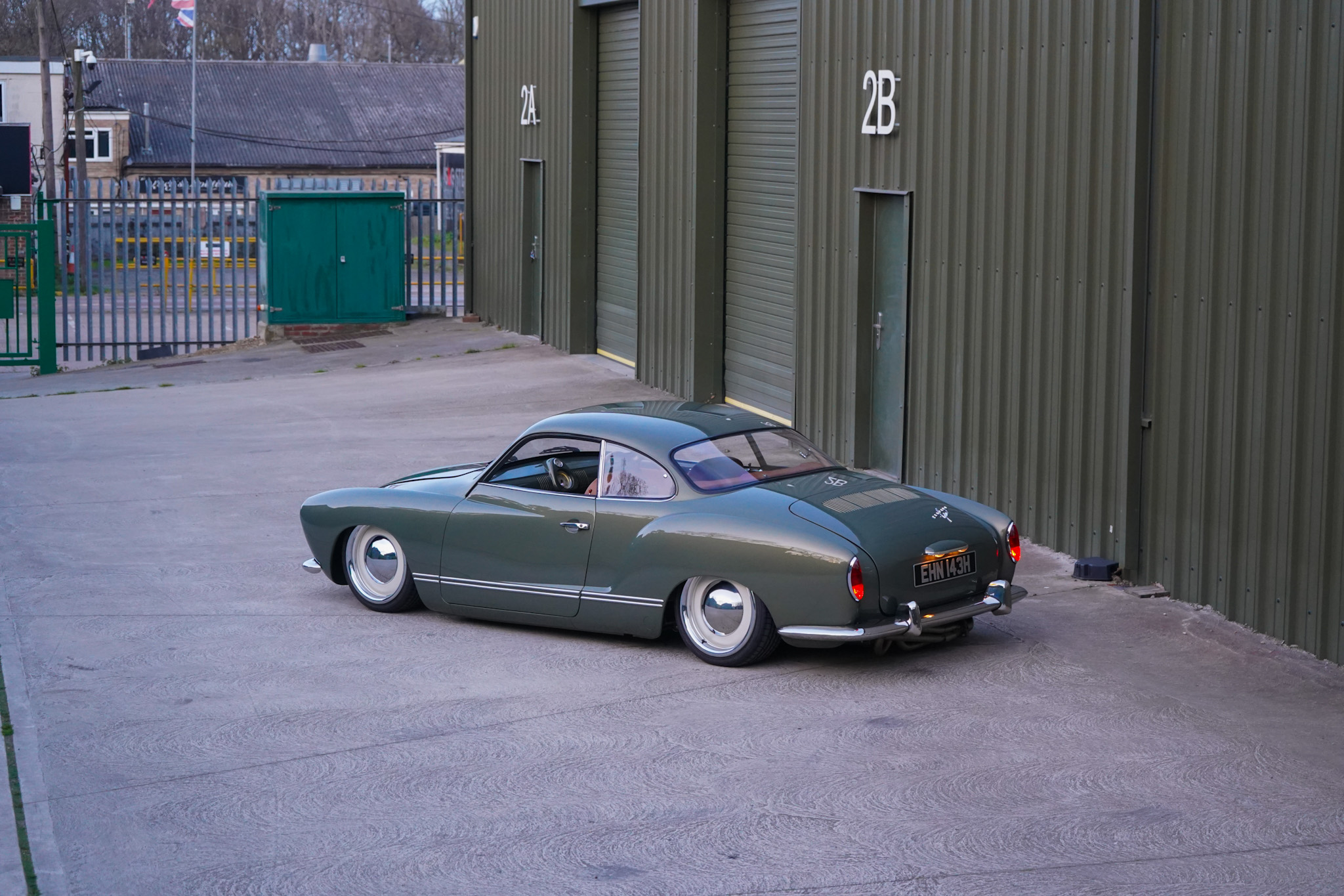 Green Volkswagen Karmann Ghia Restomod distant rear three-quarter view.