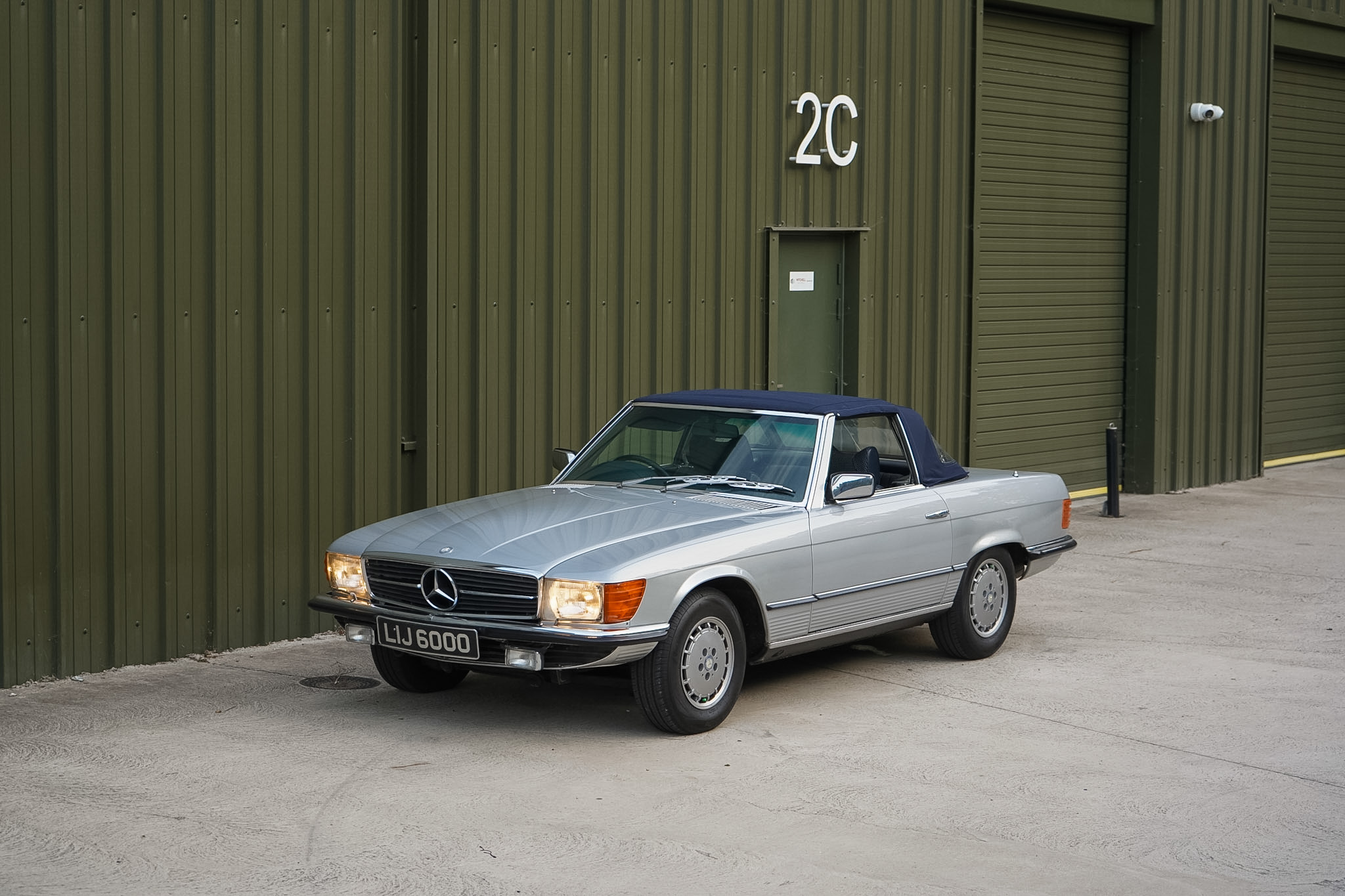 Silver Mercedes-Benz 350 SL (R107) front three-quarter view with soft top raised.
