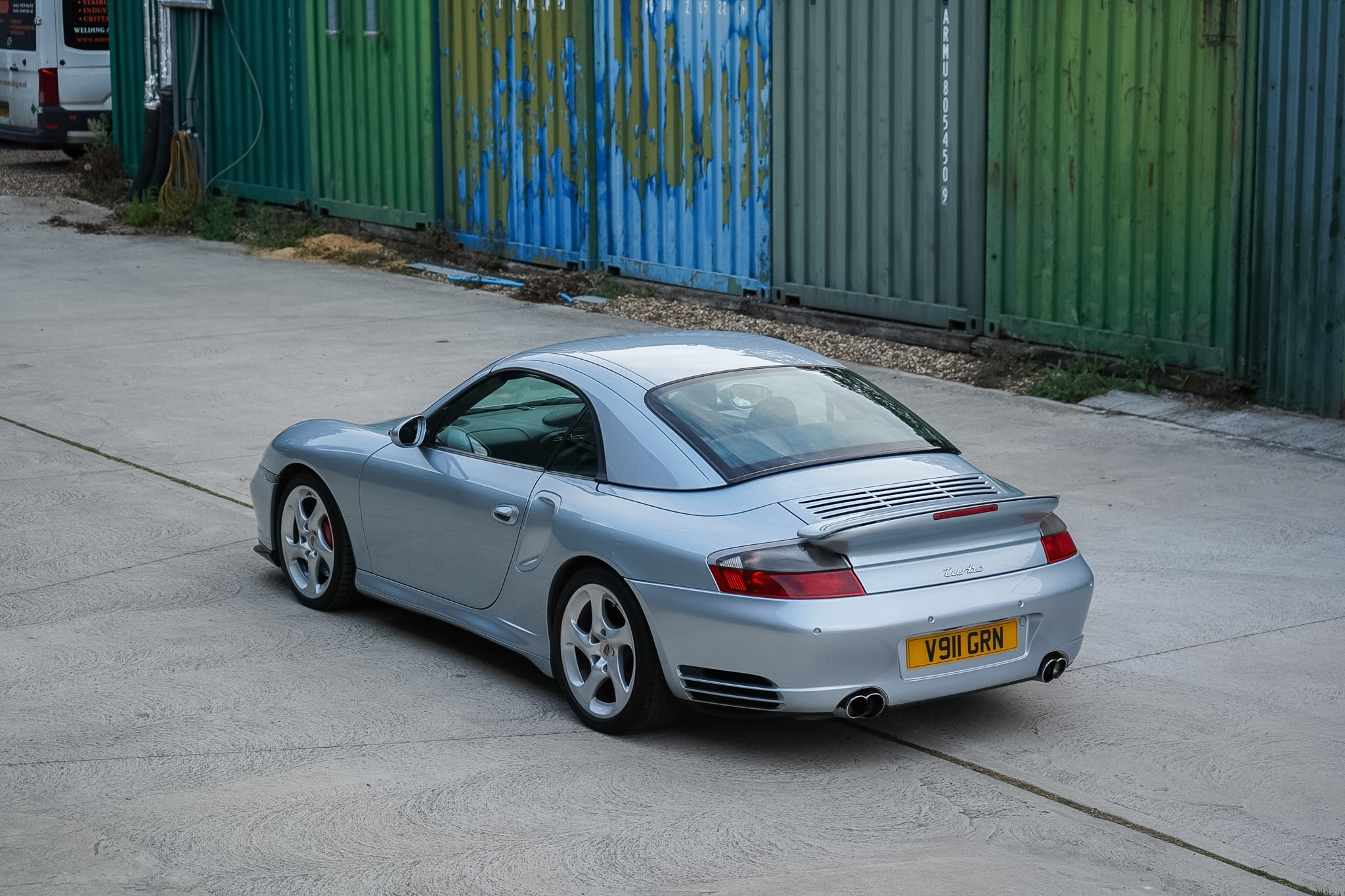 Silver Porsche 911 (996) Turbo X50 Cabriolet alternate rear three-quarter view with soft top raised.
