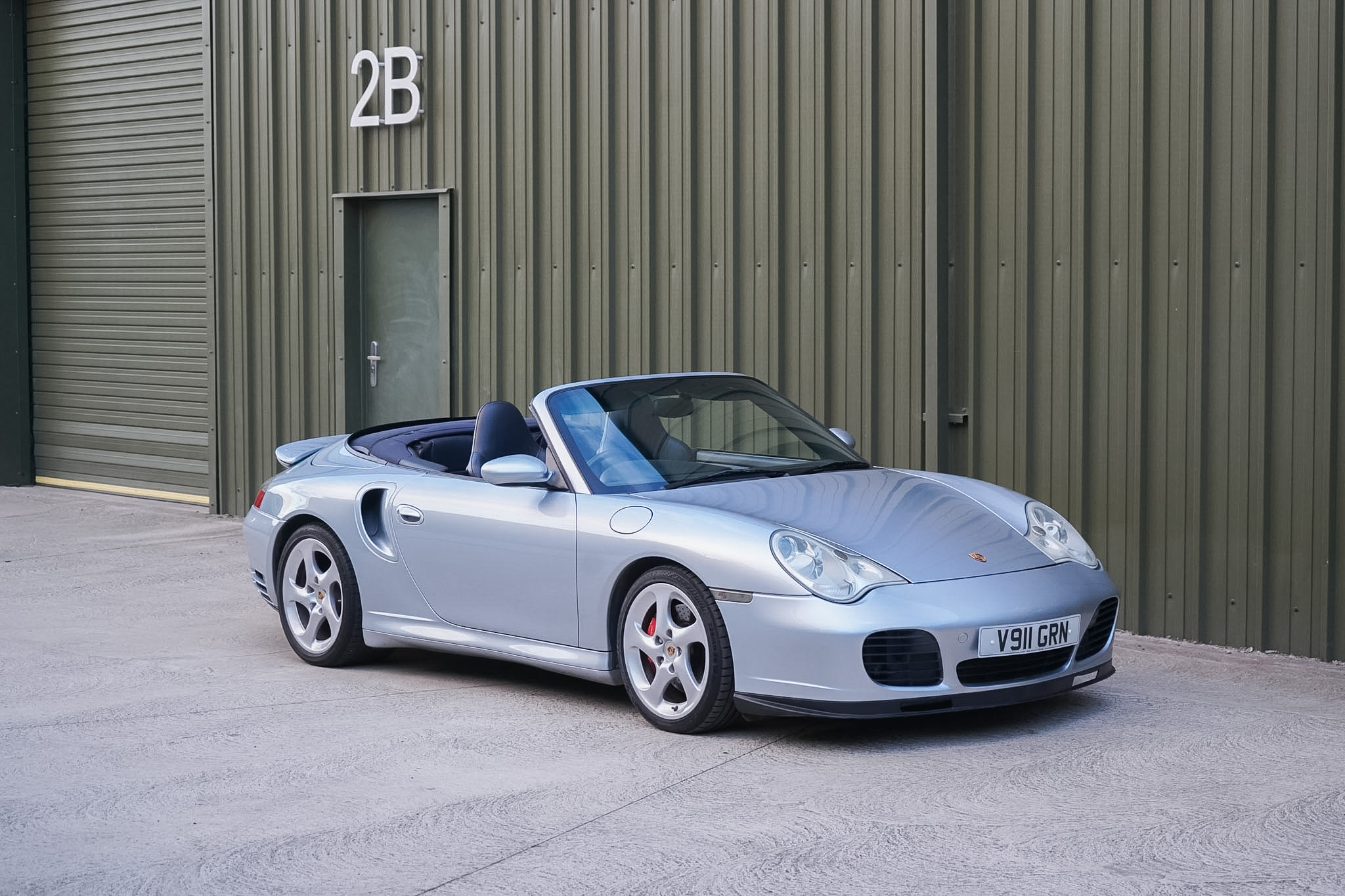 Silver Porsche 911 (996) Turbo X50 Cabriolet front three-quarter view with roof lowered from the opposite side.