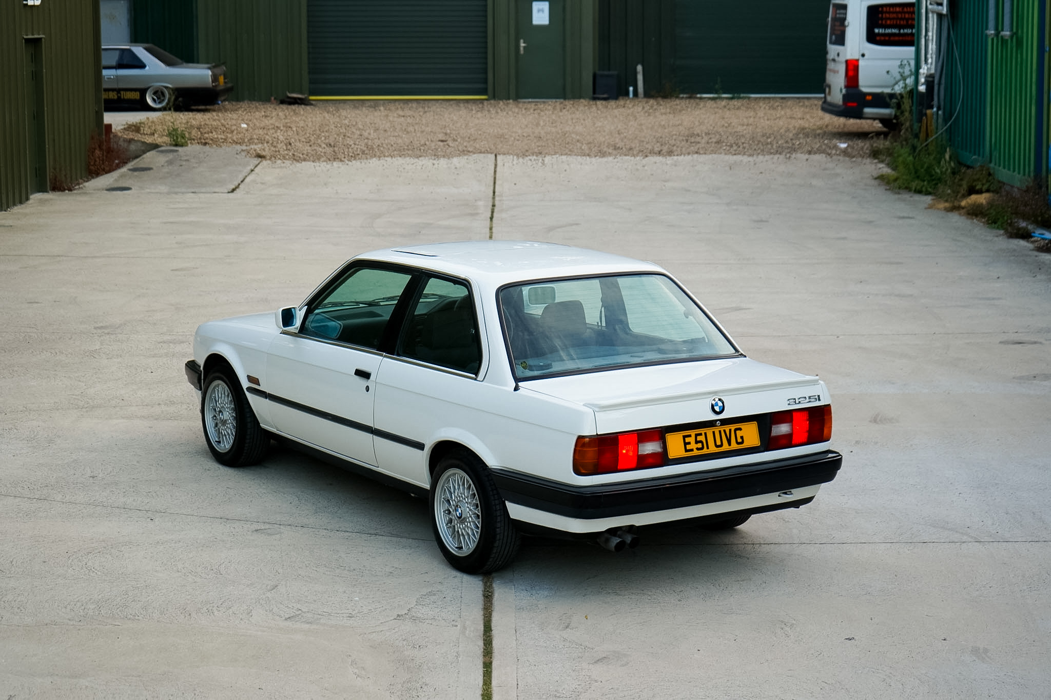 White BMW 325i (E30) Manual Coupe high-angle rear three-quarter view.