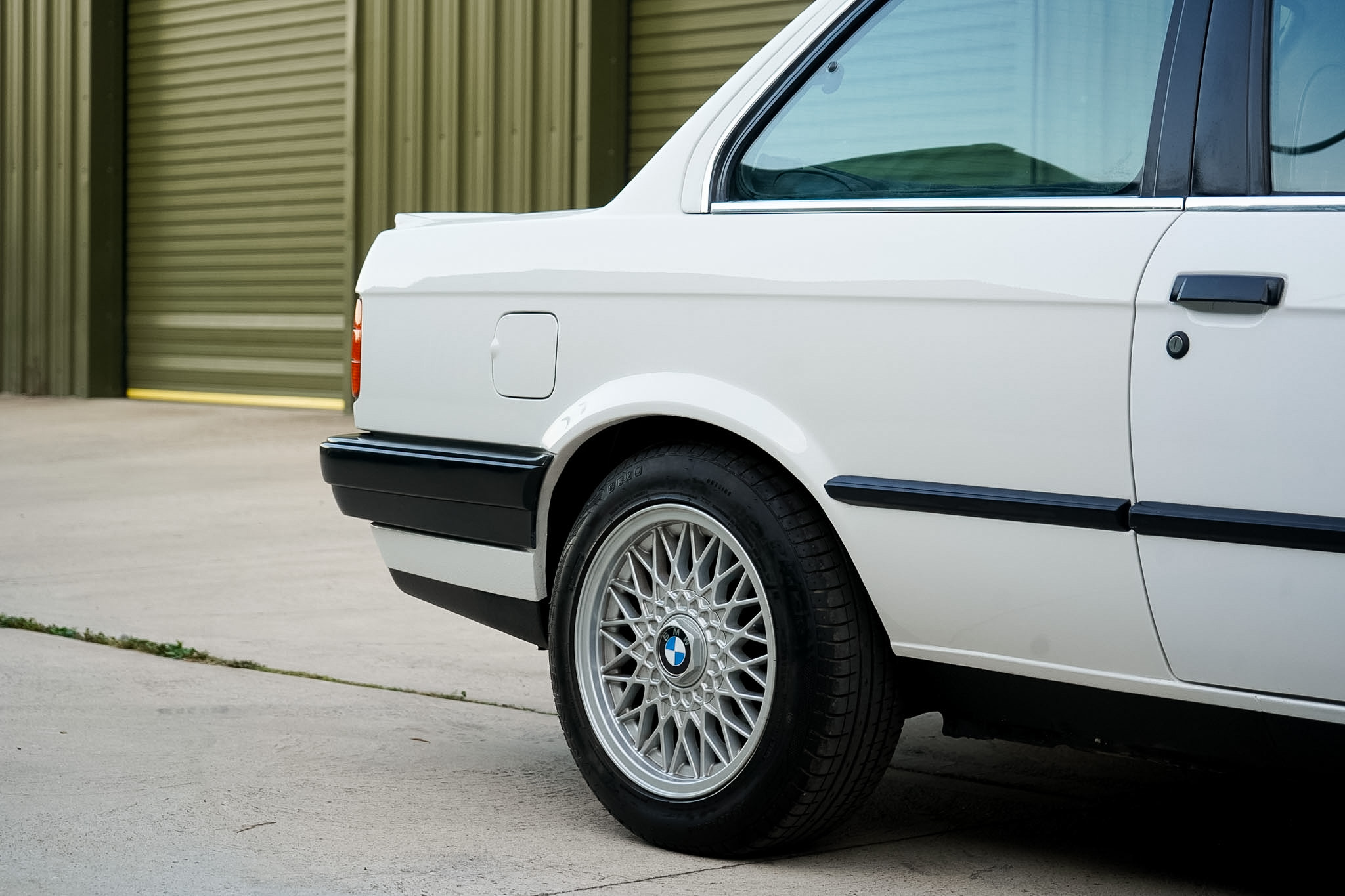 White BMW 325i (E30) Manual Coupe rear quarter and wheel side detail.