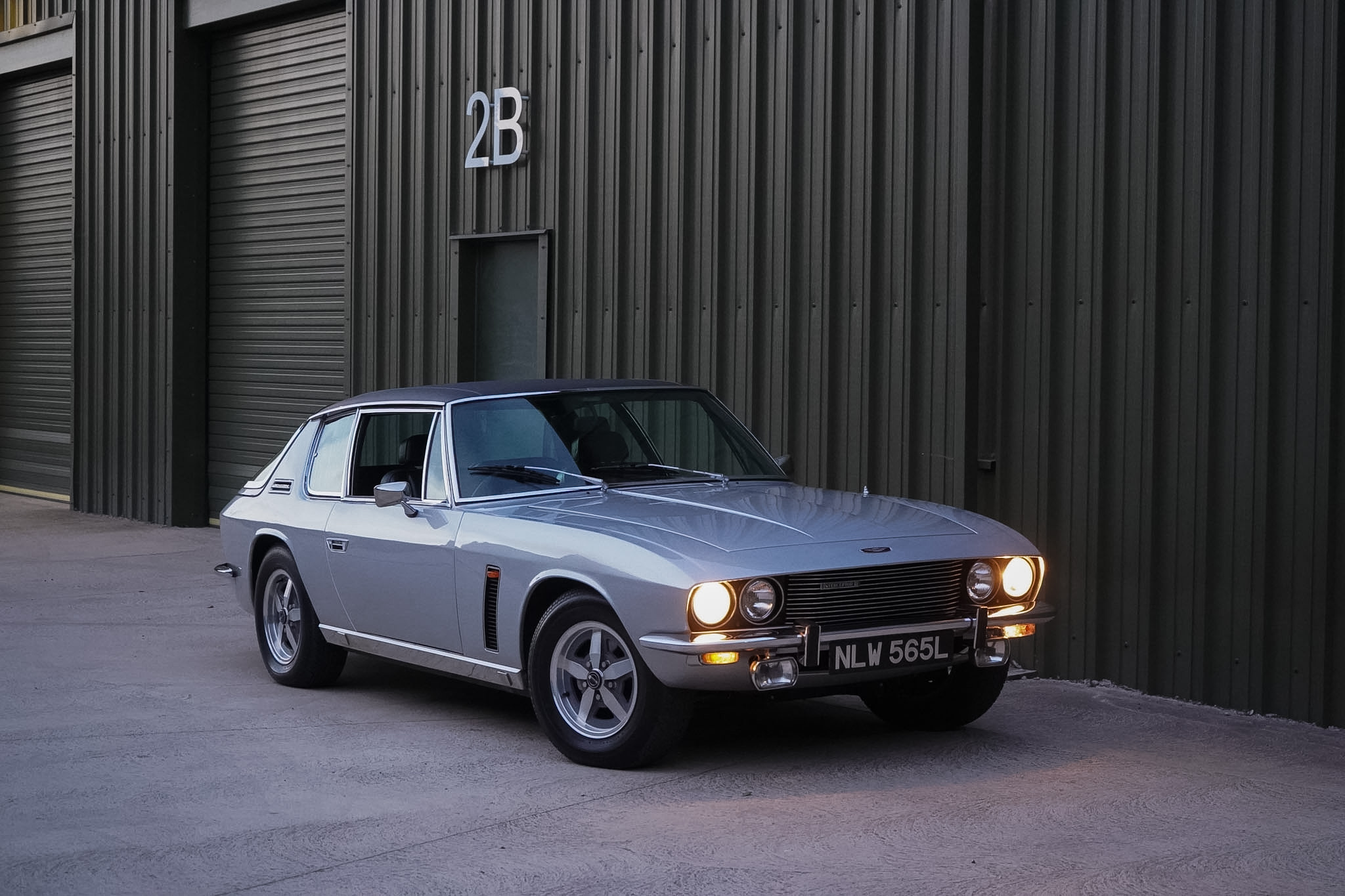 Silver Jensen Interceptor Mk III alternate front three-quarter view with lamps on.