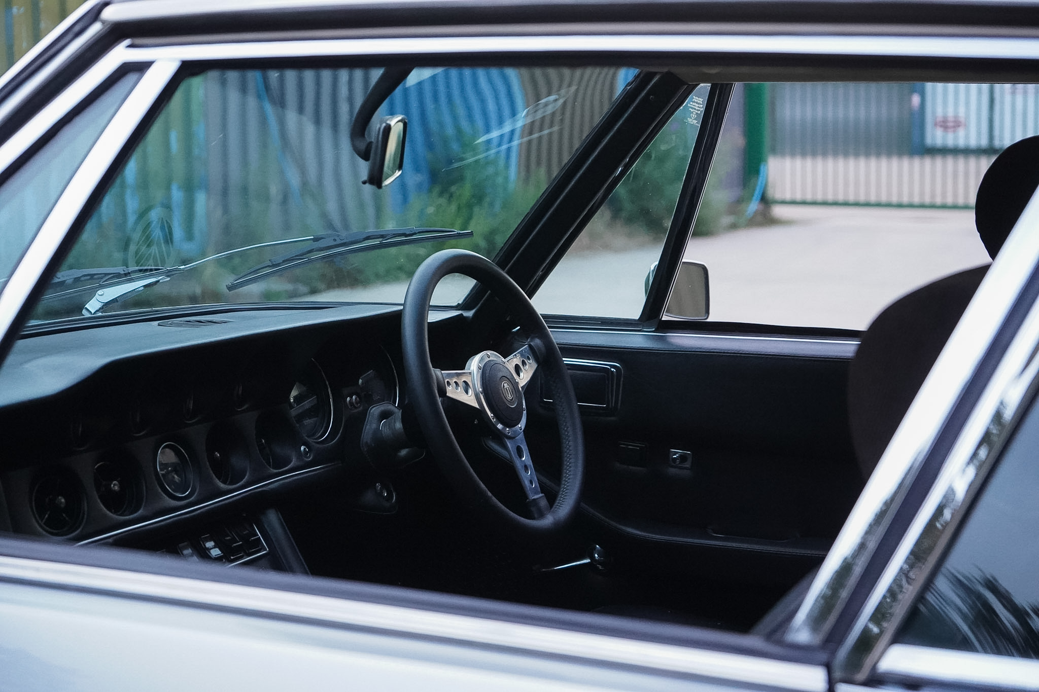 Jensen Interceptor Mk III driver cockpit viewed through the side window.